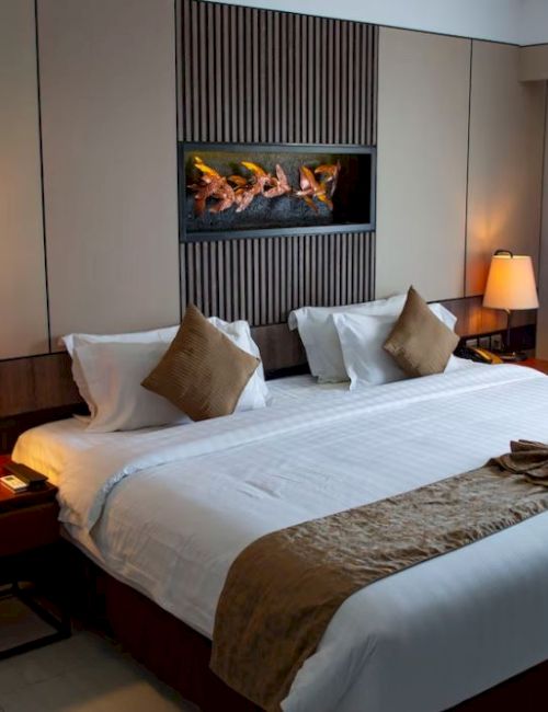 This image shows a neatly made bed in a modern hotel room, illuminated by bedside lamps with a decorative wall feature above.