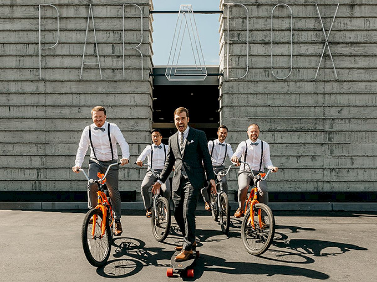 A man in a suit on a skateboard is flanked by four men on bikes, posing in front of a building with the word "PARADOX" above them.