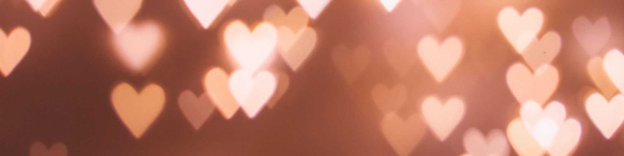 The image shows a bokeh effect with numerous heart-shaped lights in various sizes against a blurred background, all in warm, soft tones.