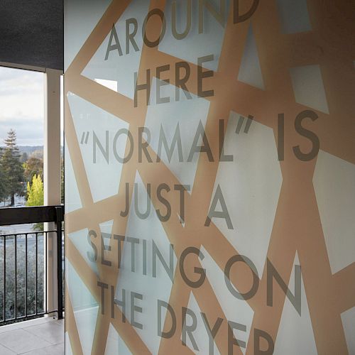 A glass wall with an artistic design featuring the text: 