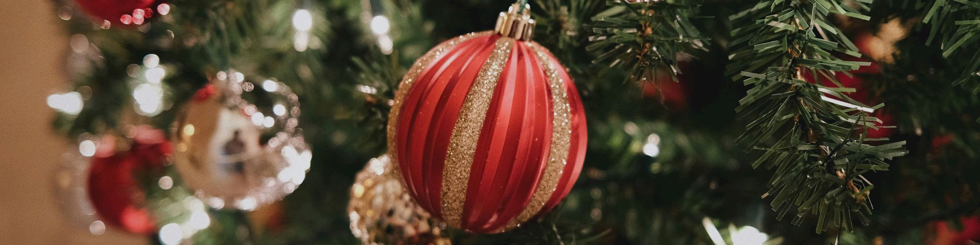 A decorated Christmas tree with red, silver, and gold ornaments and string lights is displayed.