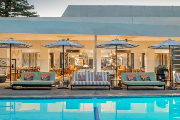 Outdoor pool area with lounge chairs, umbrellas, and a modern building in the background. The setting is serene and inviting.