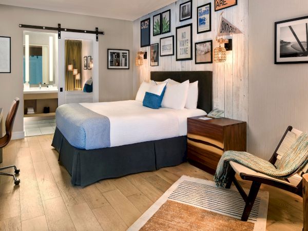 A styled hotel room with a bed, bedside table, wall art, warm lantern lights, and a bench by the window area, ready for guests.